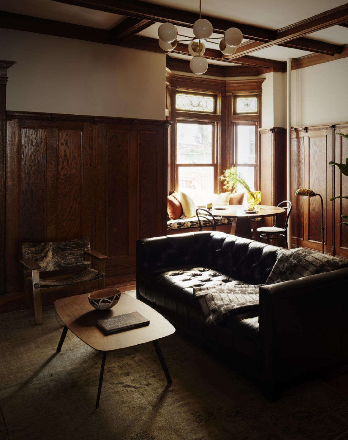 In the living room, Spain reserved the house’s warm Arts and Crafts-style wood paneling and coffered ceiling.