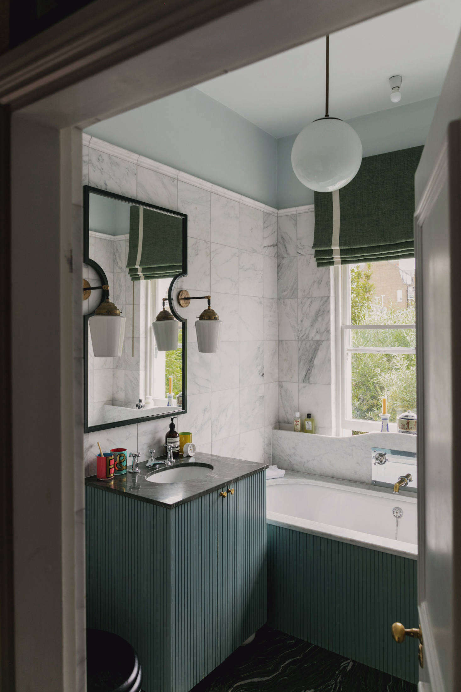 Semicircle cutouts in the bathroom mirror accommodate sconces.