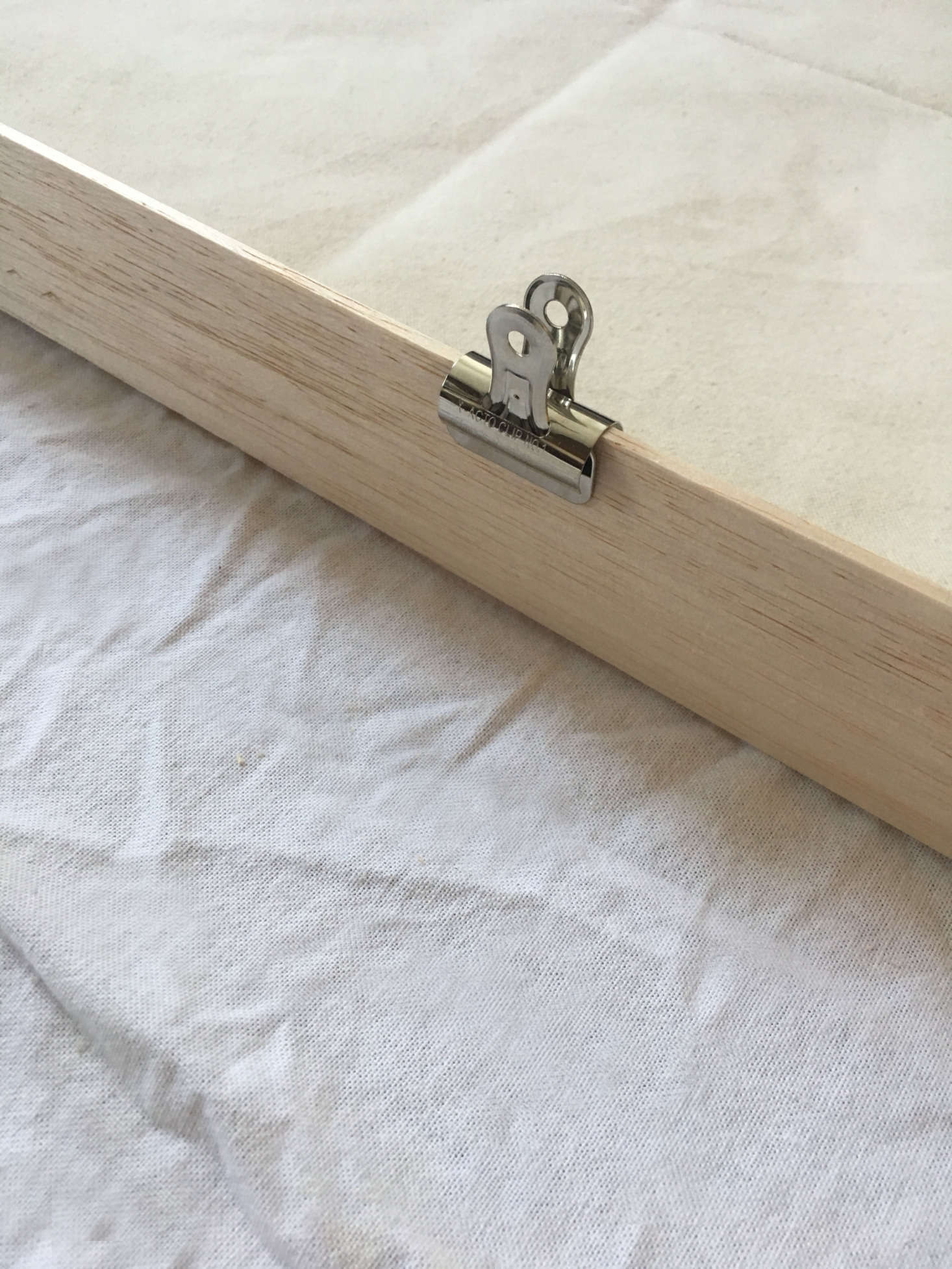Use clips or clothespins (these are bulldog clips I picked up at Blick; 59 cents each) to hold the canvas in place.