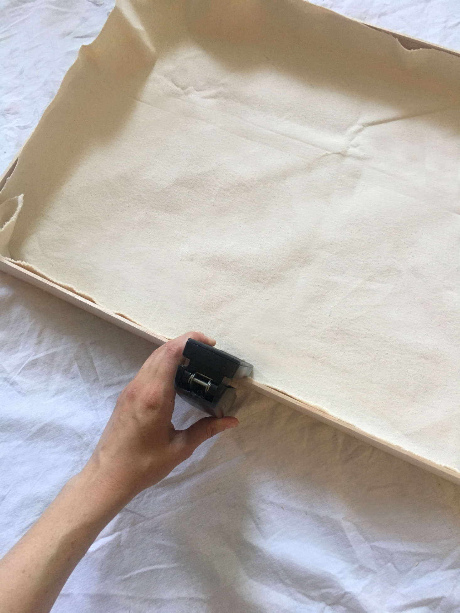 Stapling the canvas in place.