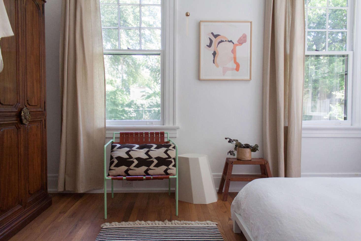 Floor-length Ikea curtains soften the look in the bedroom. The Amigo Modern chair was a gift from a friend, the wood stool a gift from Gabi’s father-in-law. A white Arnold Circus stool is used as a side table.