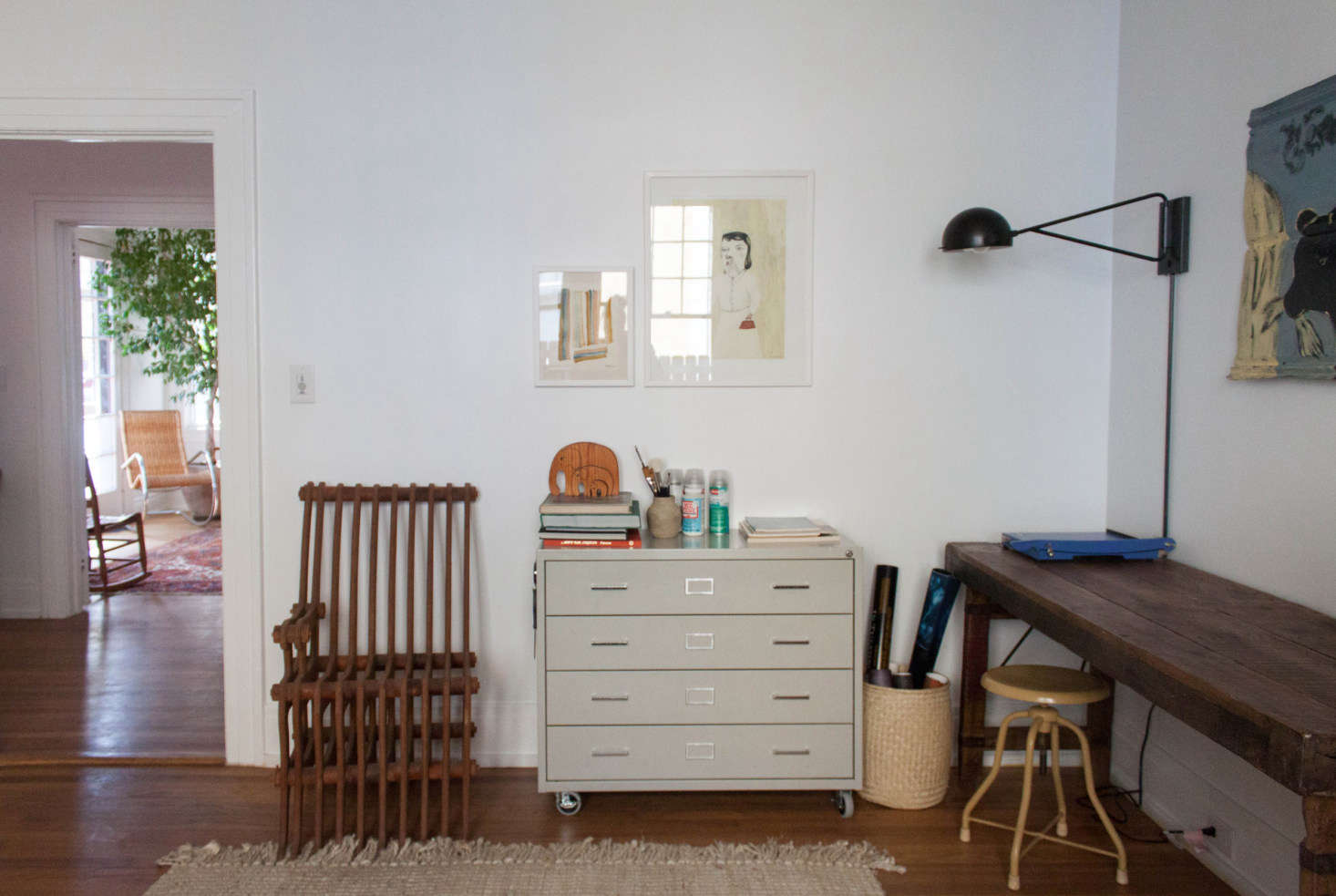 More vintage finds in this corner of the office, including a slatted chair scored at a flea market and a thrifted rolling cabinet. The wall lamp is from West Elm.