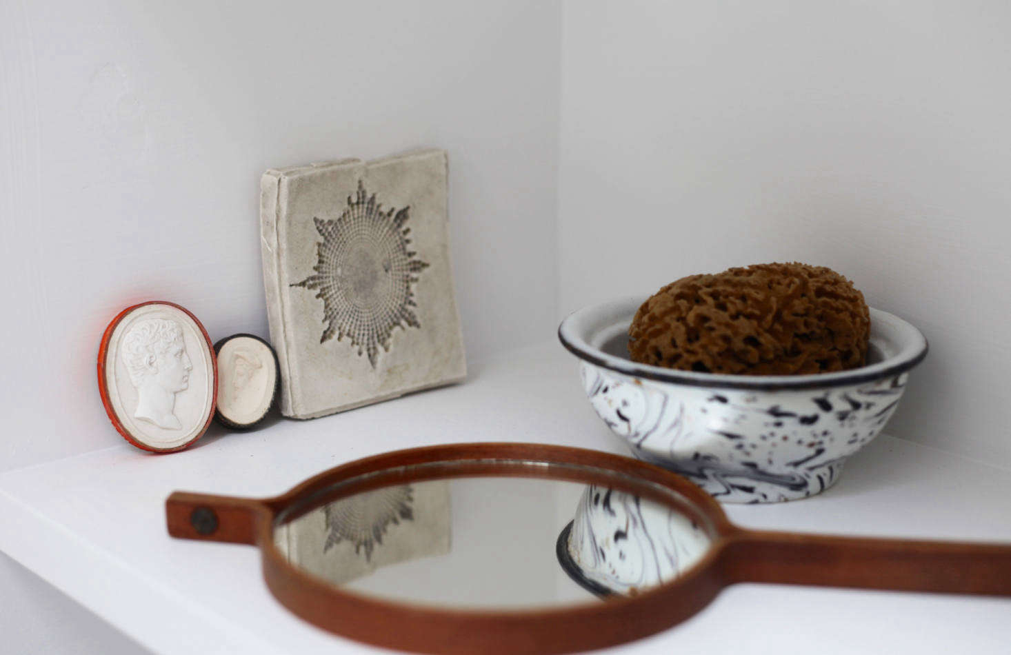 A Swedish 1950s Hans-Agne Jakobsson hand mirror and intaglios on a shelf in the upstairs bath. Photograph by Sandy Suffield.