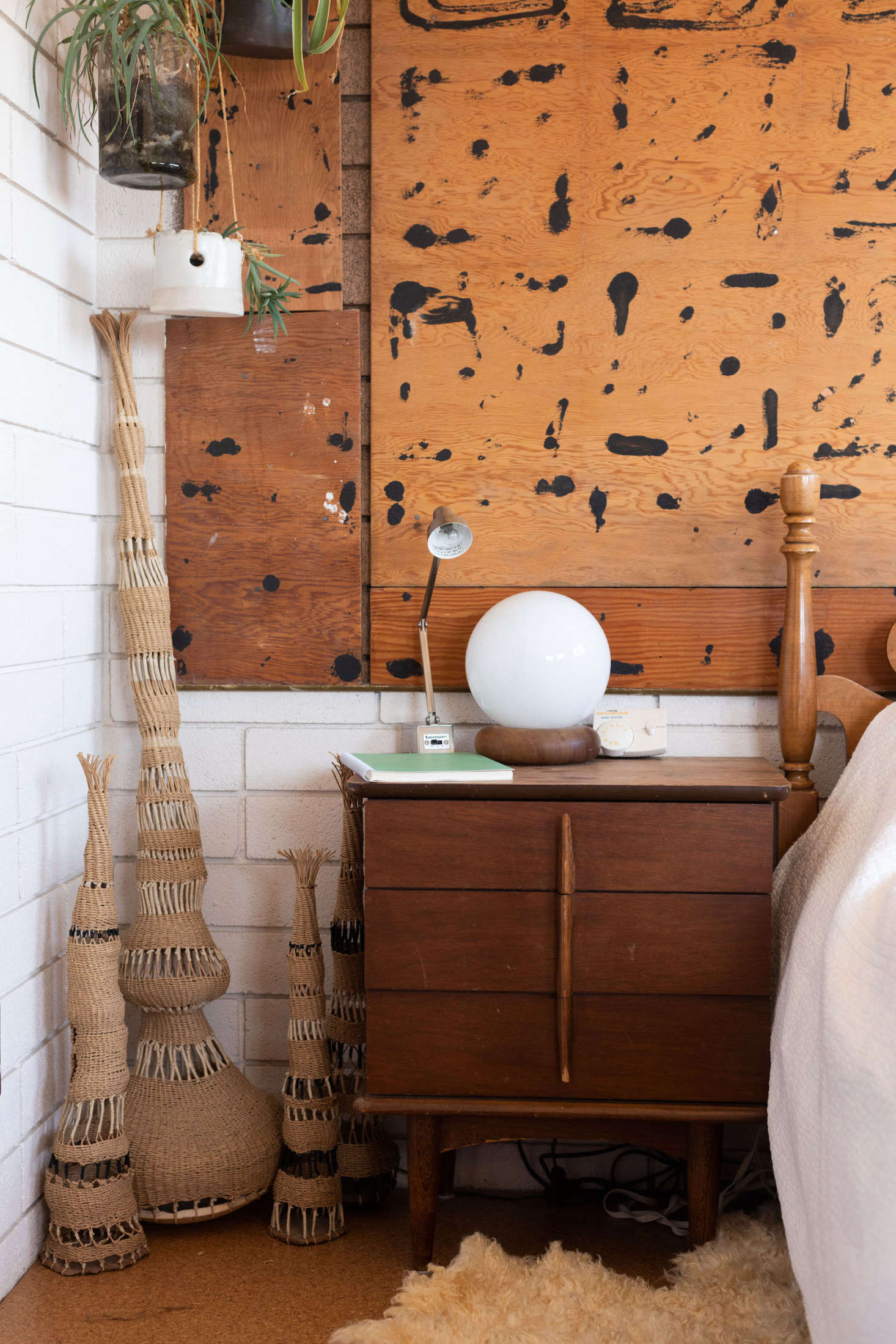 A trio of woven works anchors a corner of her bedroom. The Pollock-esque wall behind her bed is an example of Wilkinson’s love for the imperfect and improvised. The black splatters are actually the remnants of glue that remained after she removed a grid of mirrors. Her plan was to create a white wall, but after she spied the unintentional art on the plywood, she decided to keep it.