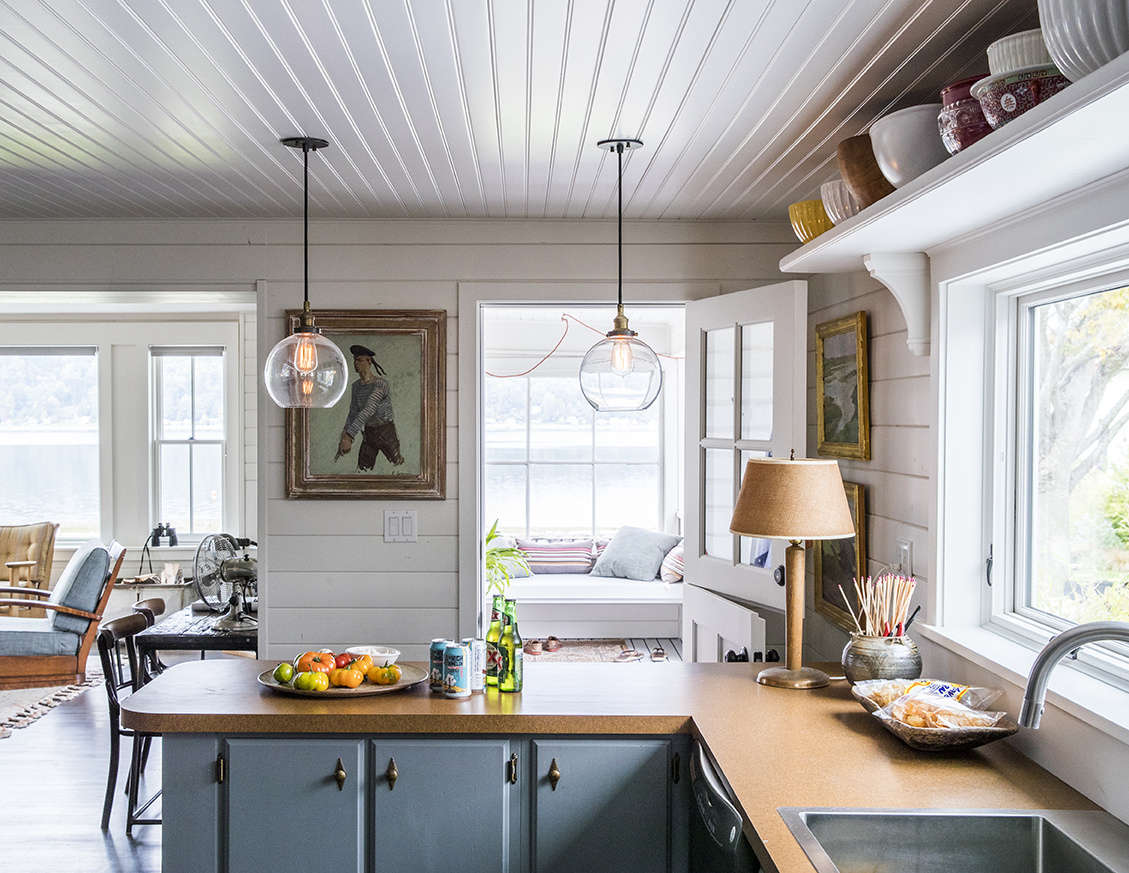 The only element that survived the renovation? The 1950s kitchen cabinets, now painted a gray-blue and appointed with brass hardware for a nautical feel. Formica countertops (new) further the old beach-cottage story.