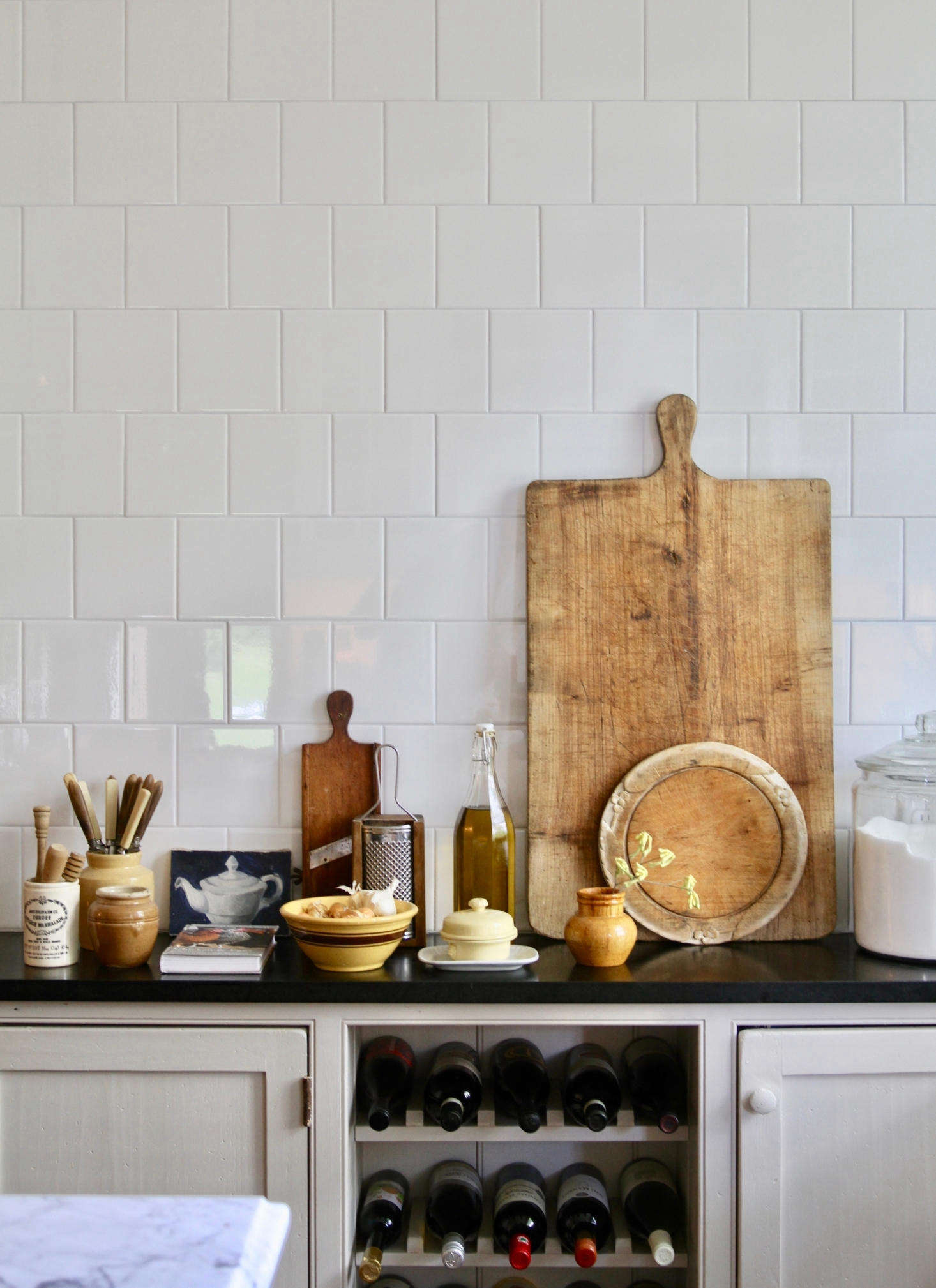 Simple square white tiles in the kitchen. The couple are geniuses at layering textures, spotlighting patina, and finding beauty in the mundane.