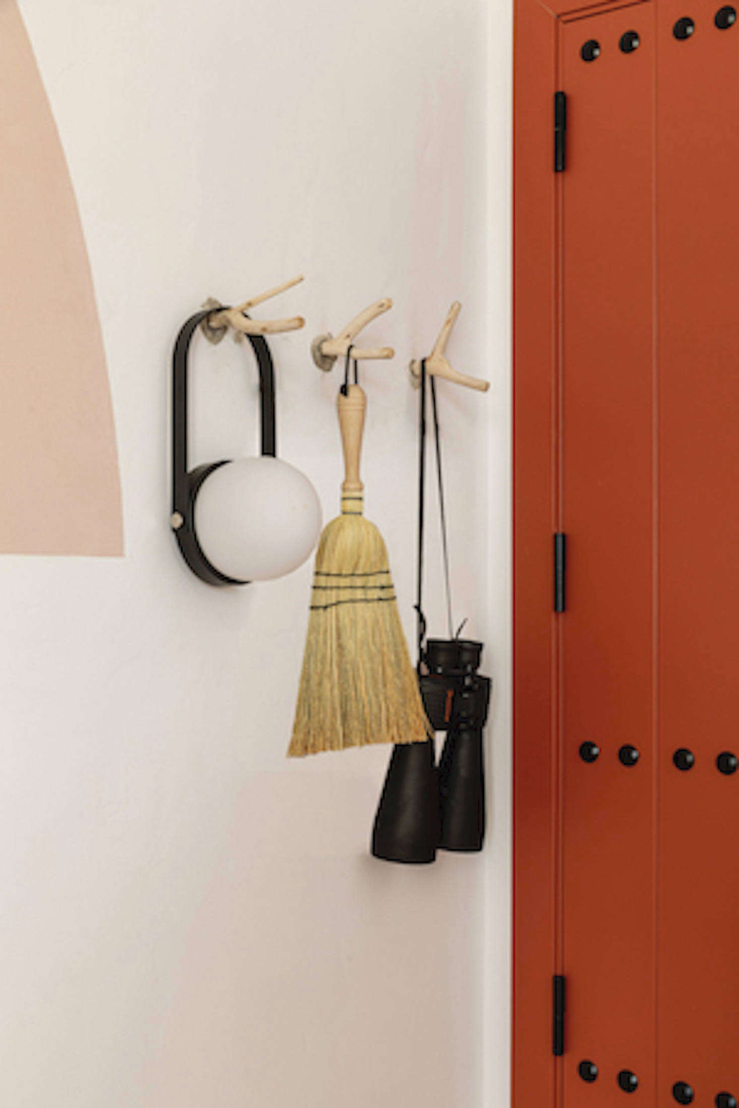 Guest rooms have modern-rustic paneled doors in Meilichzon’s bold riff on terra-cotta. Hooks whittled from twigs on the property hold accessories guests might want to use while exploring, including a Carrie Portable LED Lantern.