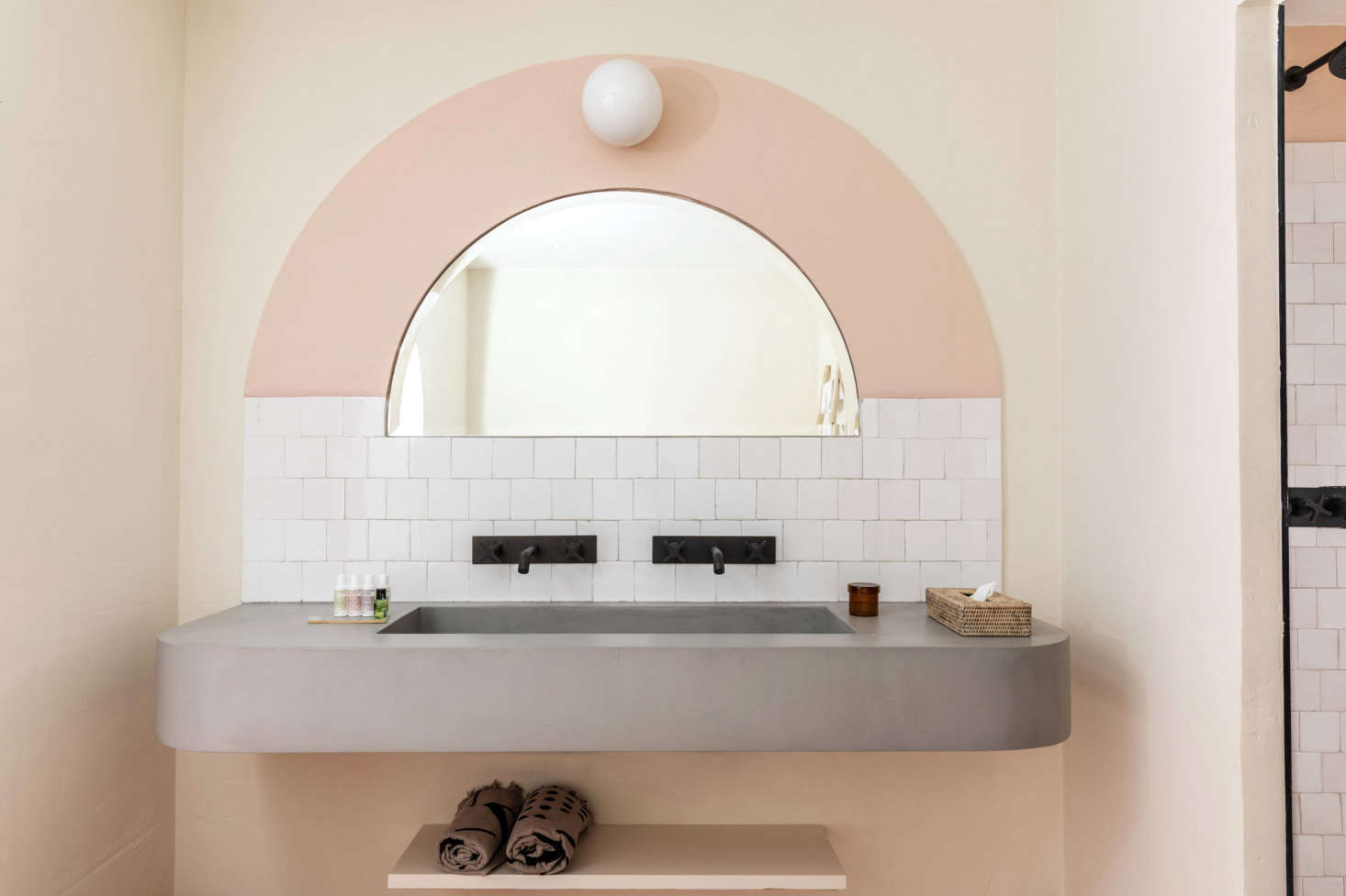The painted arches are a clever way to introduce color without fully going to town. The sinks are made of local stone finished with a thin layer of concrete. French enameled tiles serve as a backsplash.