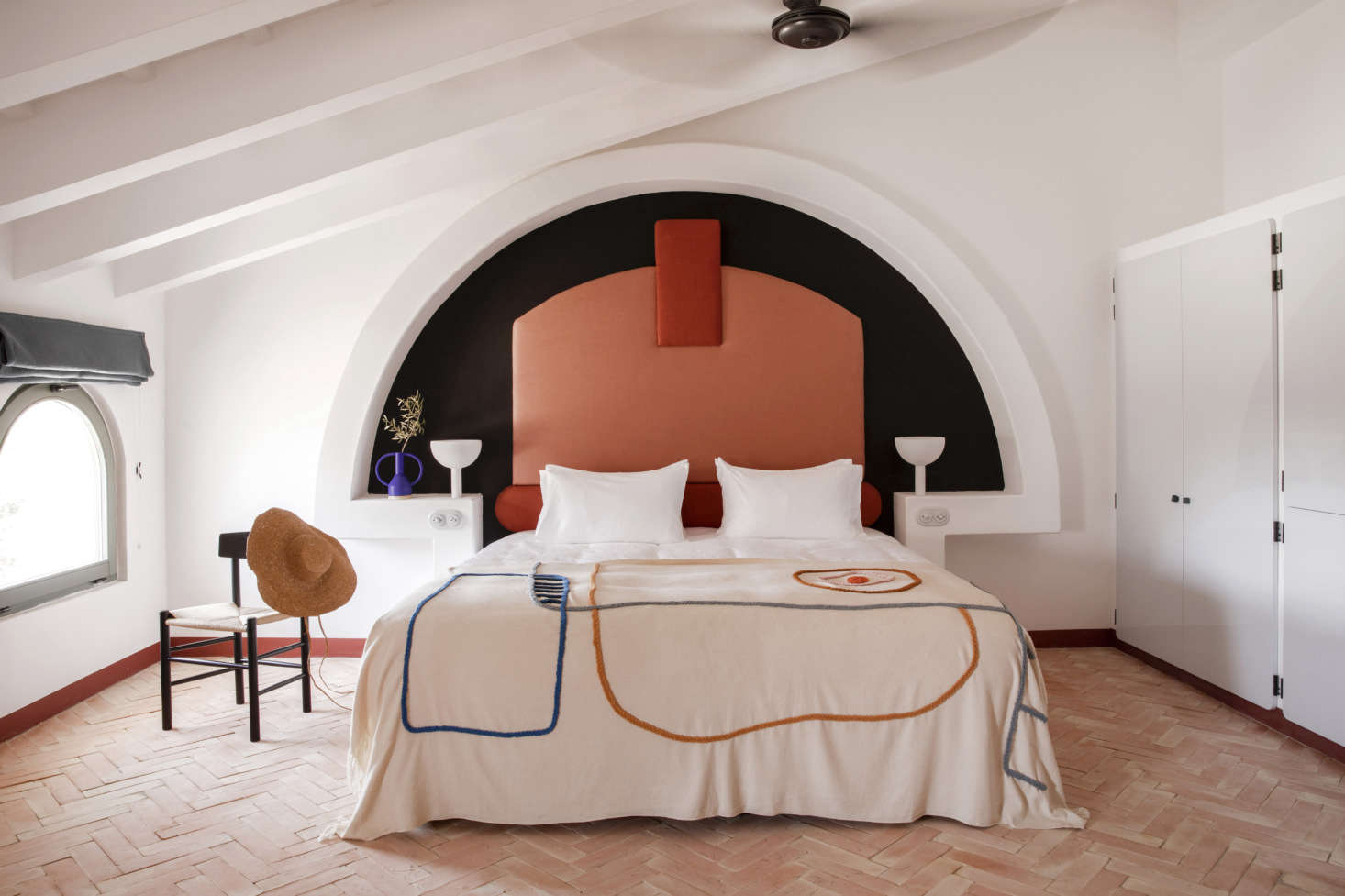 Meilichzon is known for her inventive beds—and never repeats herself. At Menorca Experimental, she built altar-like concrete alcoves finished in white lime and inset with upholstered headrests in two shades of terra-cotta. The embroidered cotton bedspreads were made for the hotel by textile and ceramic studio LRNCE of Morocco. The herringbone floor is composed of terra-cotta.
