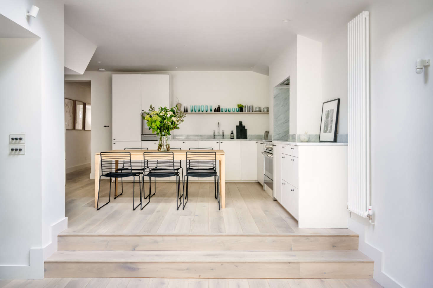 The open kitchen is in the addition. Stackable chairs from Hay surround a handcrafted table by Ethnicraft. Note the stylish light switches (at left): 