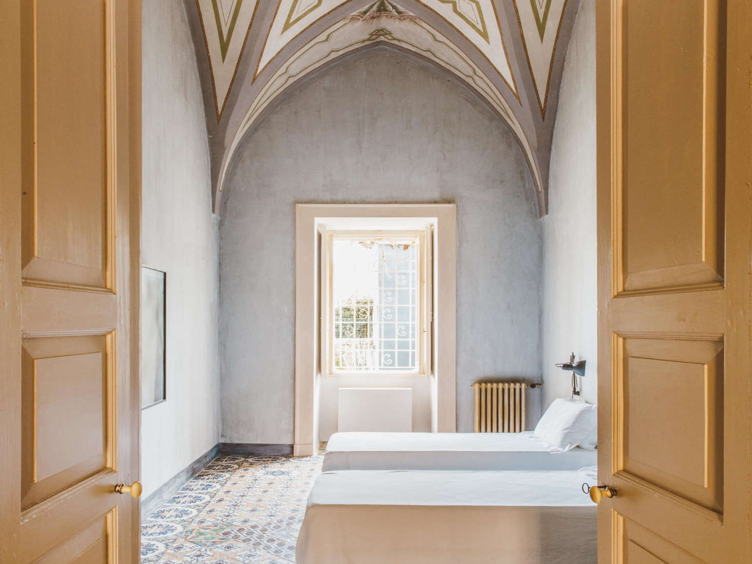Another guest bedroom is left almost completely undressed so that the bones—a dramatic vaulted ceilings and double doors painted entirely in yellow—are the focus.
