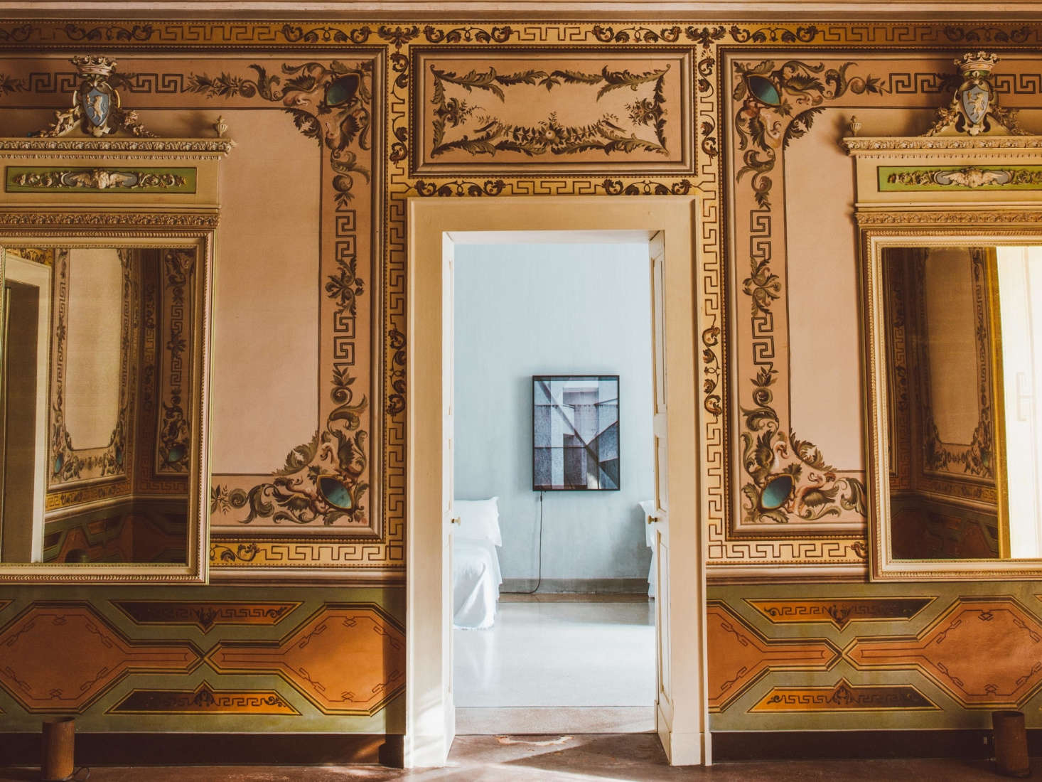 A particularly ornate hallway, with gold-hued frescoes and mirrors, leads to one of the suite’s pale guest rooms.