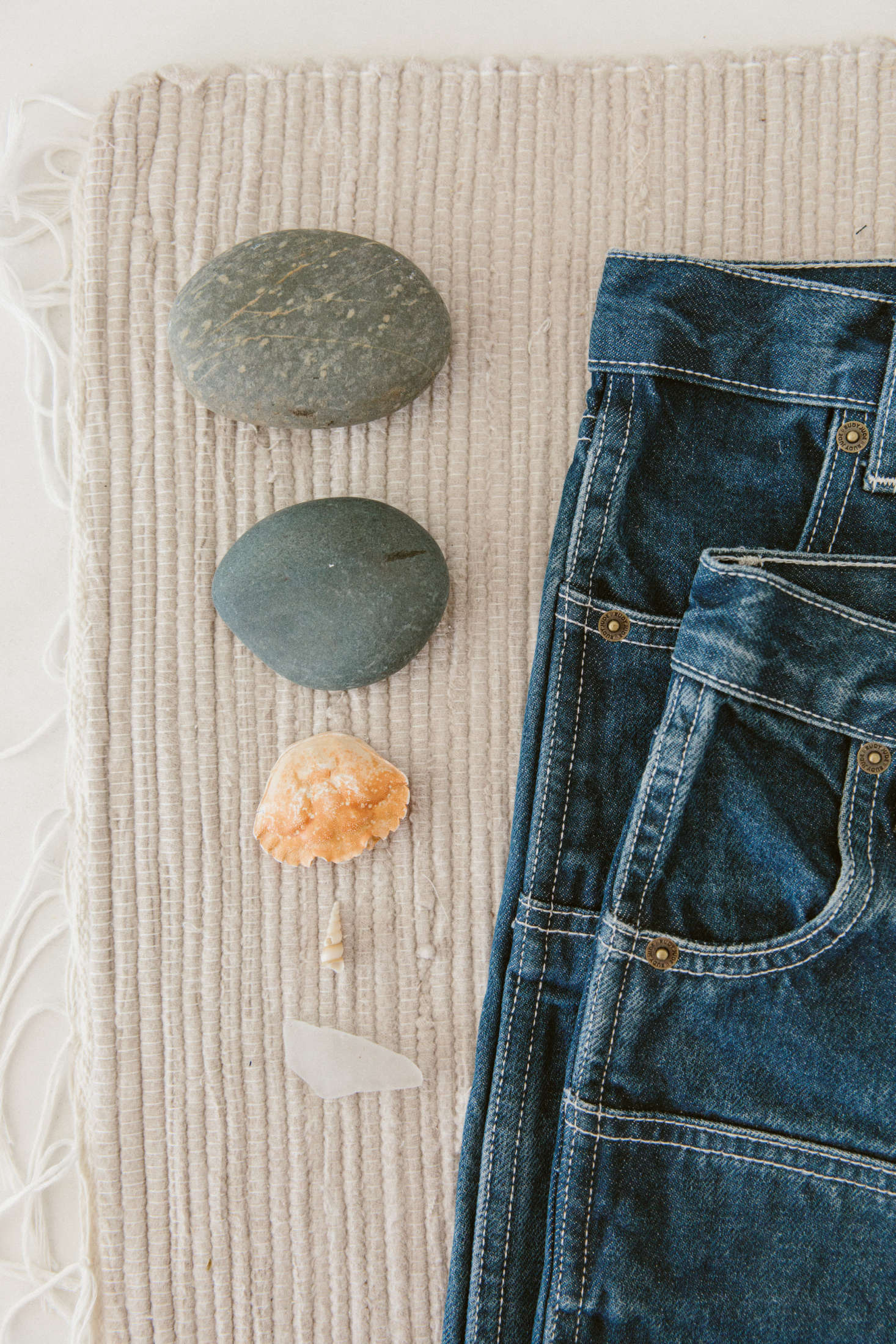 Smooth rocks and a hollow crab shell next to some Rudy Jude denim.