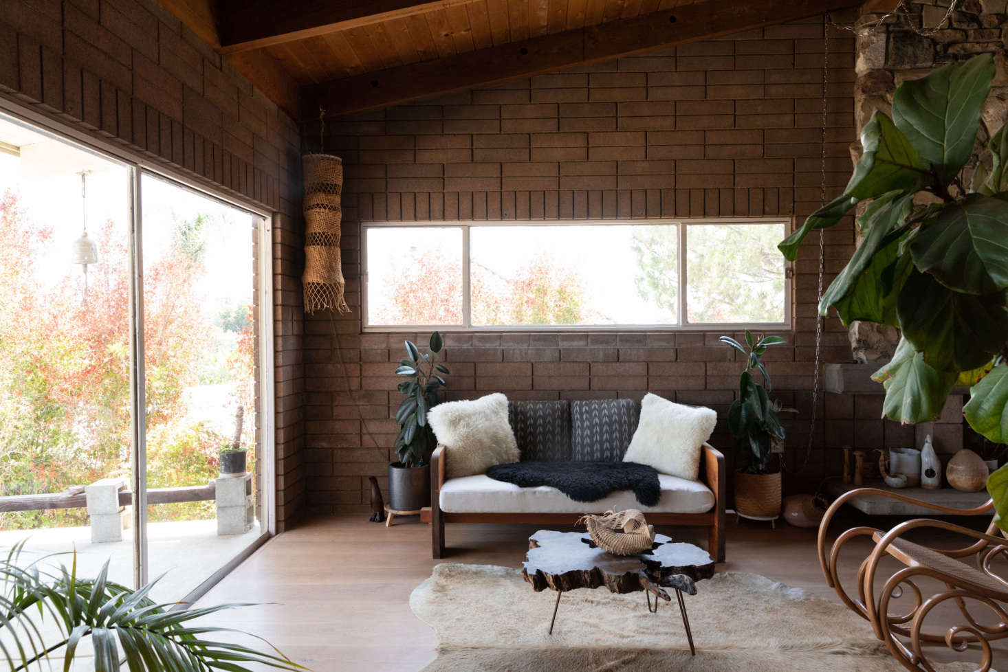 Wood-paneled ceilings and brick walls keep the house cool on hot days. Hanging in the corner is one of her woven raffia creations.
