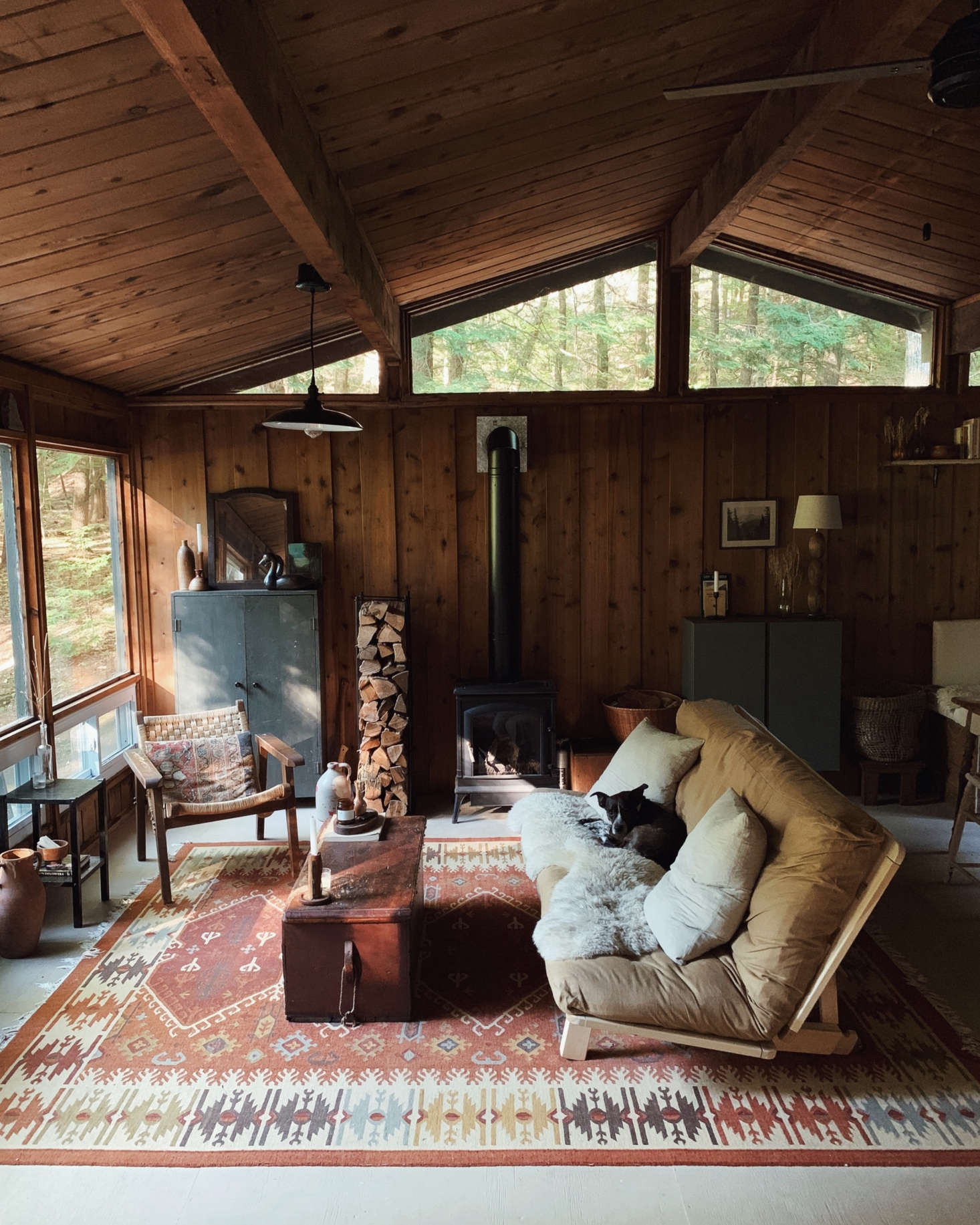 The cabin’s living room, with a futon by KD Frames. The cabinet on the back wall, by the window, is the one that inspired much of the interiors. The rug was part of the package: “It’s important to me to keep a little piece of the previous family in the cabin,” Saunders says.