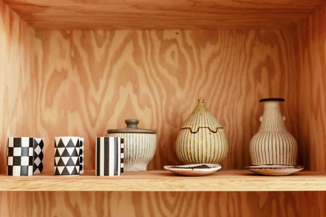 Of the choice of plywood, Yanai says, “In keeping with the humble bones of the house, I wanted to work with simple industrial materials and not get precious with exotic veneers.” The black-and-white Mori Mini Sake Cups are by Masahiro Mori