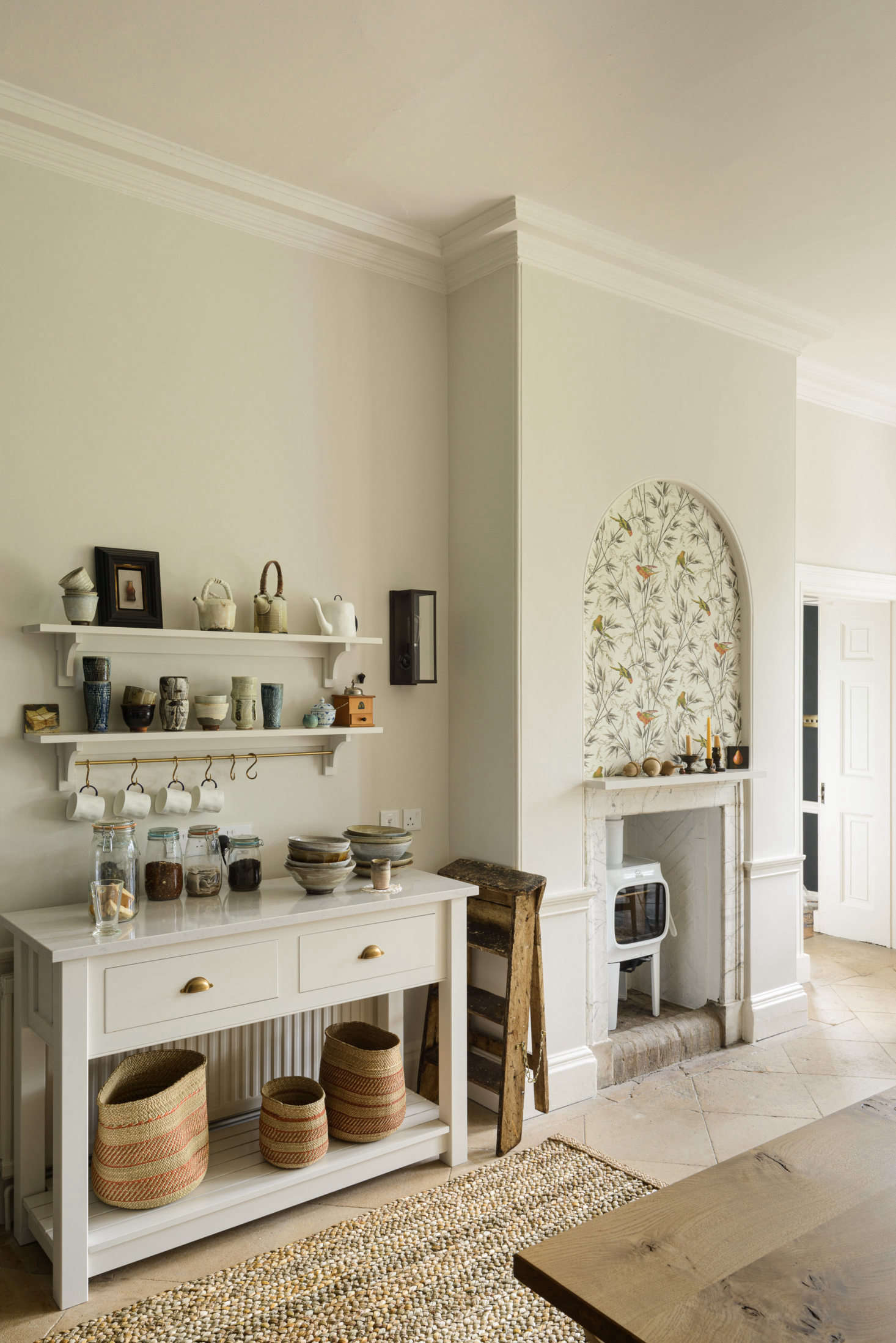 Across from the island is a console set up for tea-making. Whimsical wallpaper by Little Greene Paint & Paper (in 