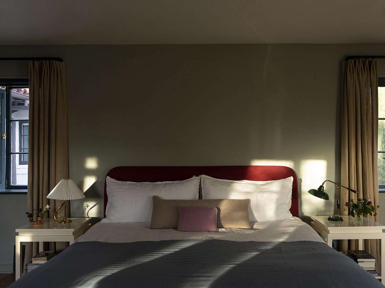 The custom headboard and bedskirt are in a deep burgundy linen. Parachute Linen Sheets are topped with a Once Milano Linen Summer Throw.