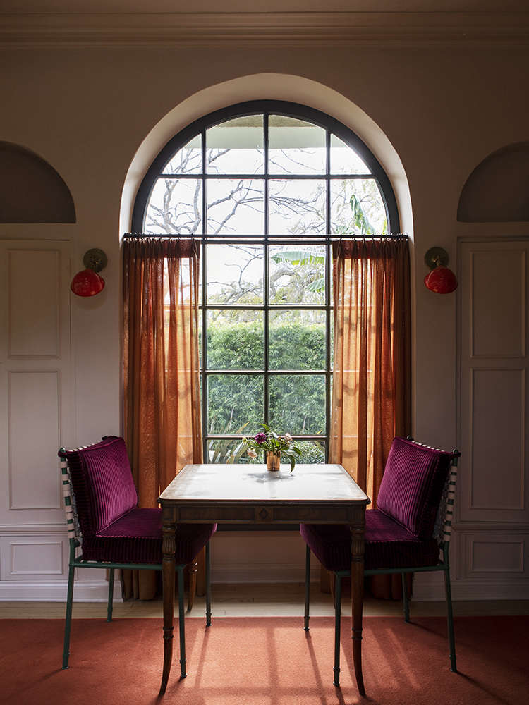 A favorite color moment: curtains in a linen from Bart Halpern against Casa Midy Altavista chairs cushioned in crimson corduroy from Pindler & Pindler. The antique table is used for playing chess and backgammon. The red sconces, from the family
