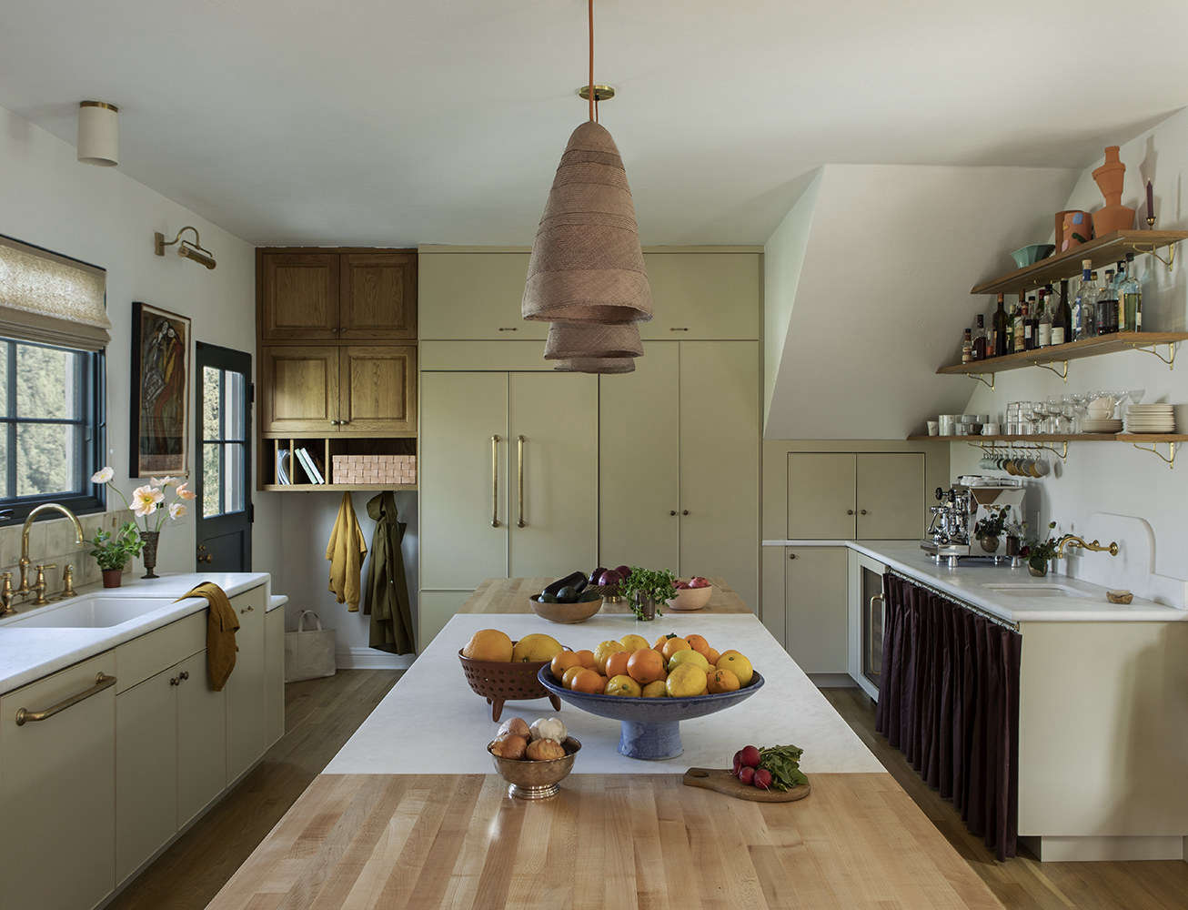 Space gained from removing the pantry wall was devoted to a coffee and bar sink. A lot of storage is artfully incorporated along the back wall: next to the door, in lieu of a mud room, Merrill created a 