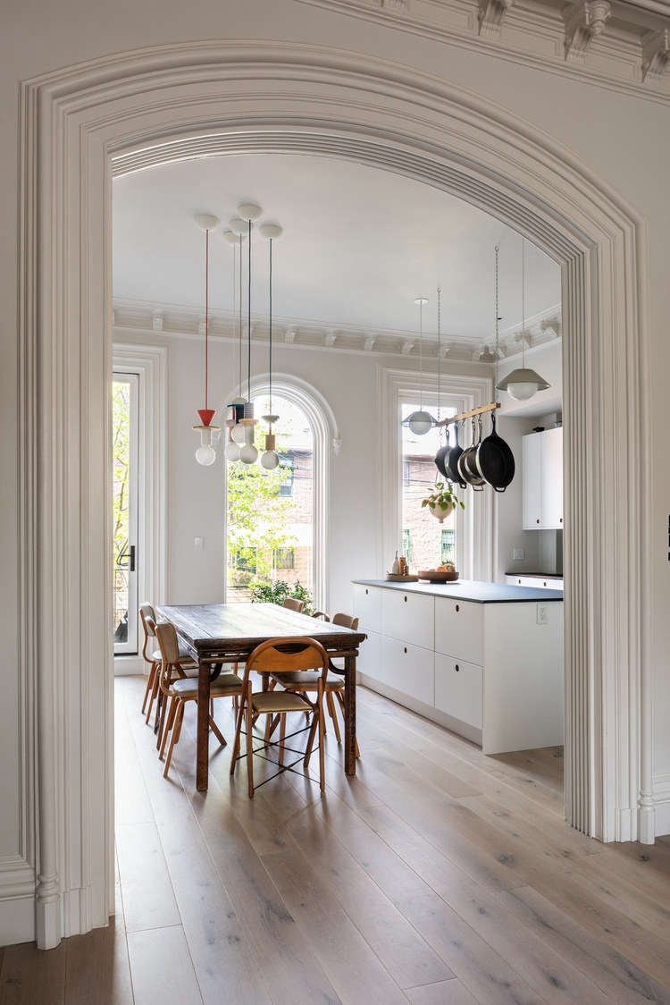 Hanging above the vintage dining table are five painted-wood Junit Pendant Lights designed by Julia Jessen. A pair of Akoya Pendants by Rich Brilliant Willing hover over the island.