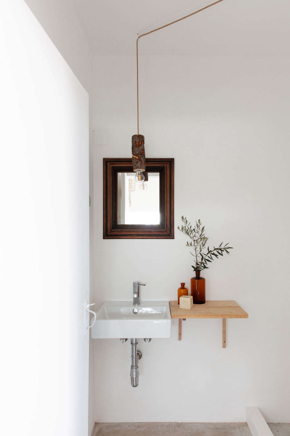 A wood ledge extends sink-side space in one of the baths. Note the rustic pendant light, too.