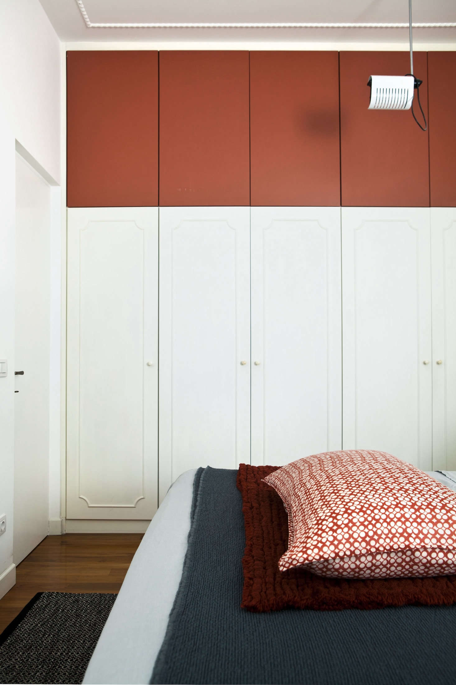 In the bedroom, the architects integrated existing built-in wardrobes with an added row of storage on top, painted also, strikingly, in Tuscan Red.