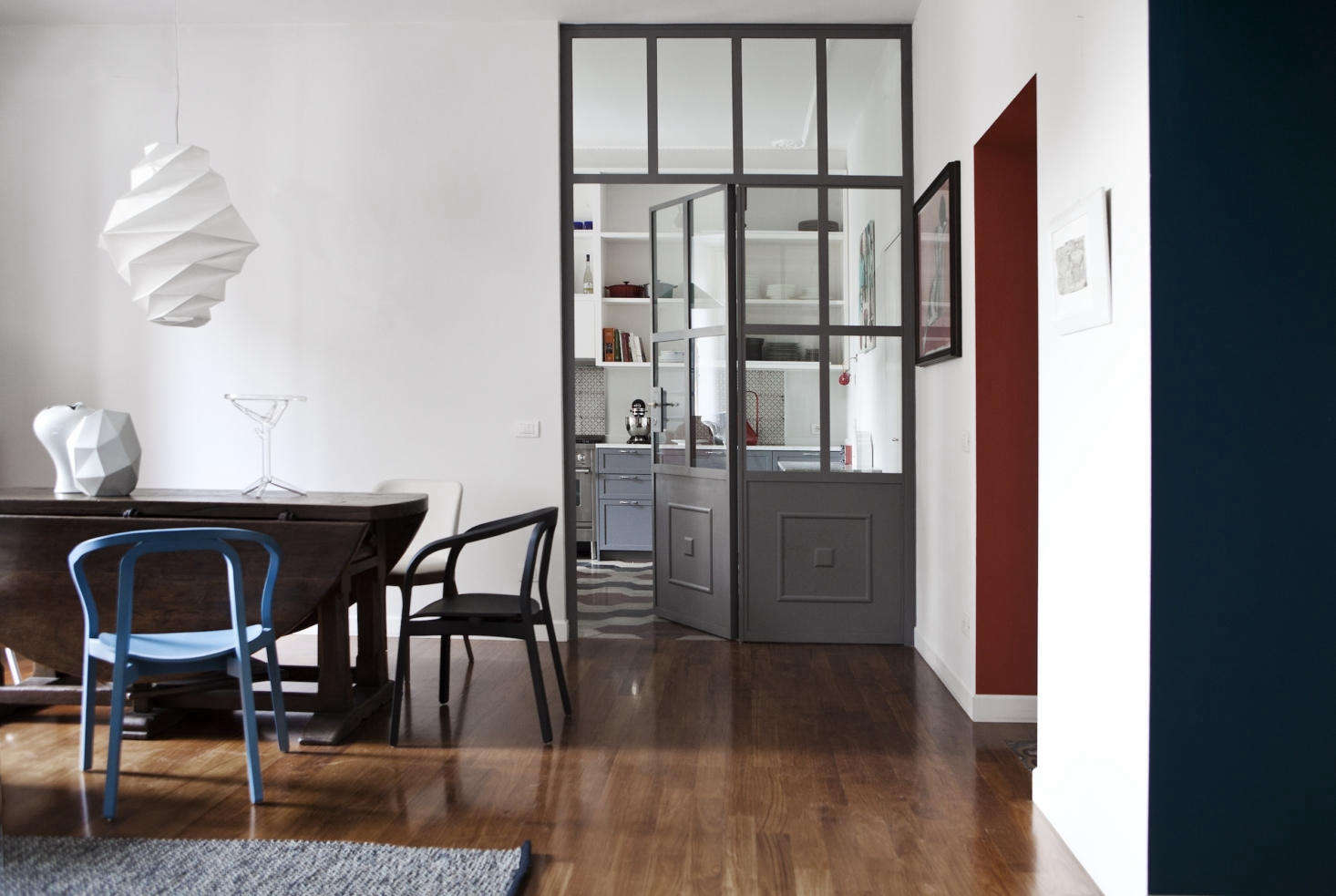 The kitchen opens onto the dining area, where a family heirloom table pairs with blue Evoque by Miniforms chairs.