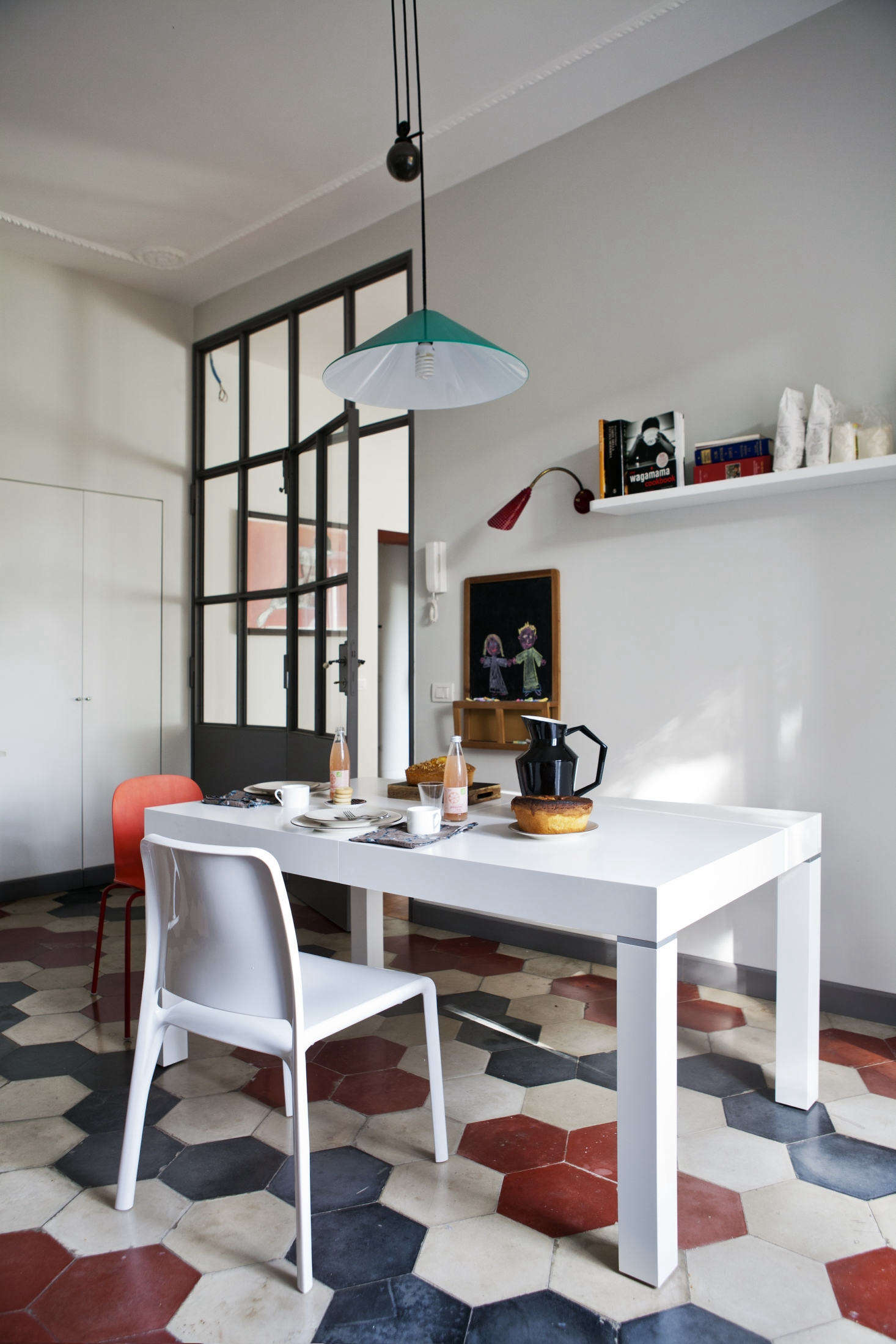 A bright turquoise pendant—the Aggregato by Artemide—hangs above the breakfast table.