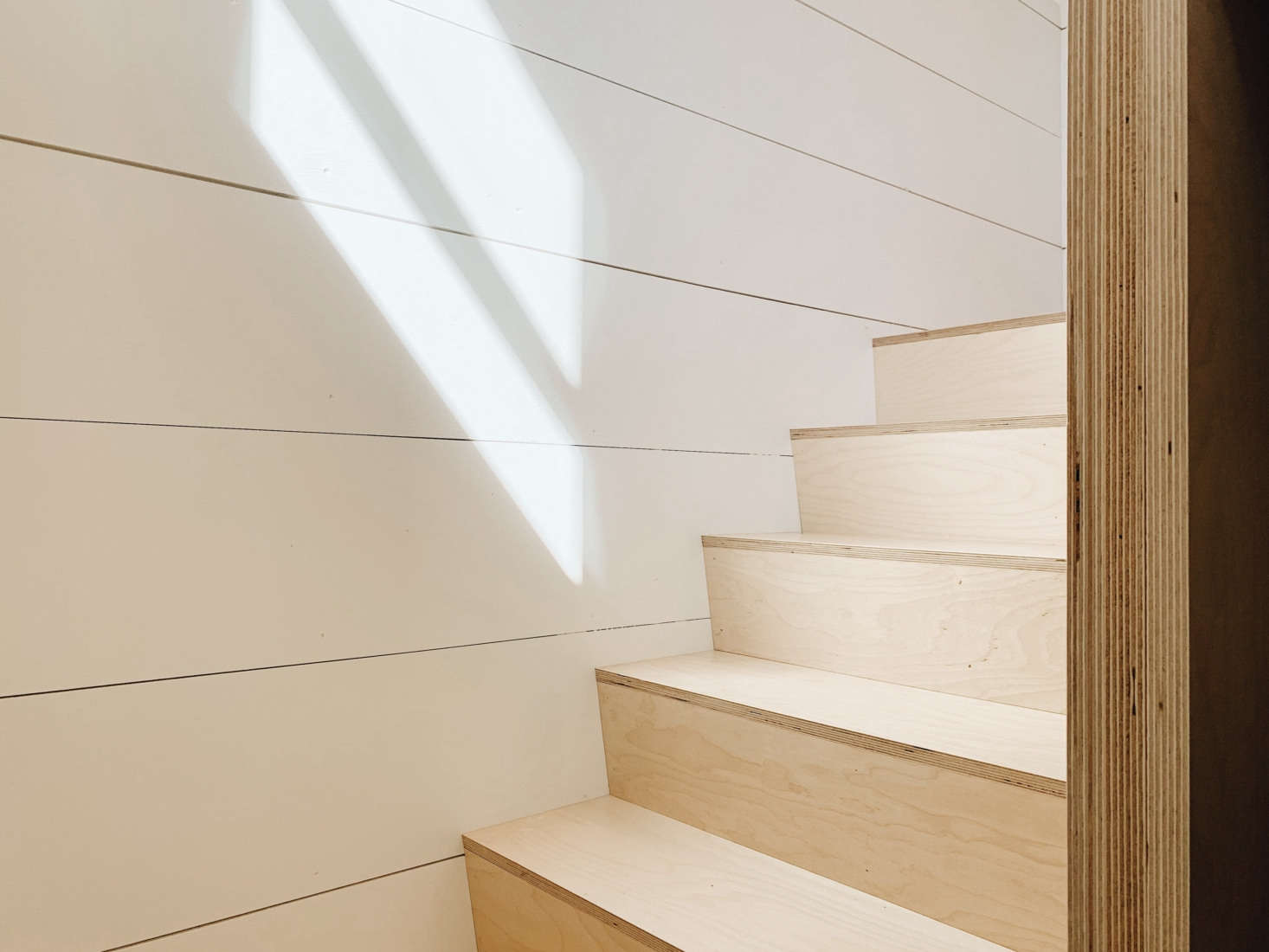Shiplap paneling and birch plywood stairs. Note the door frame