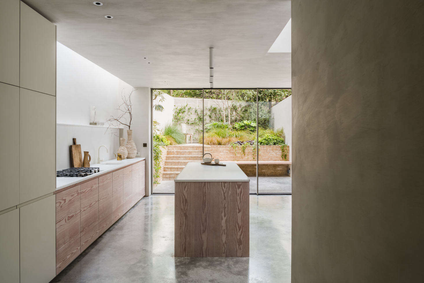 O nível do porão apresenta piso de concreto polido por toda parte e se estende até o jardim, logo após as portas de correr da cozinha.