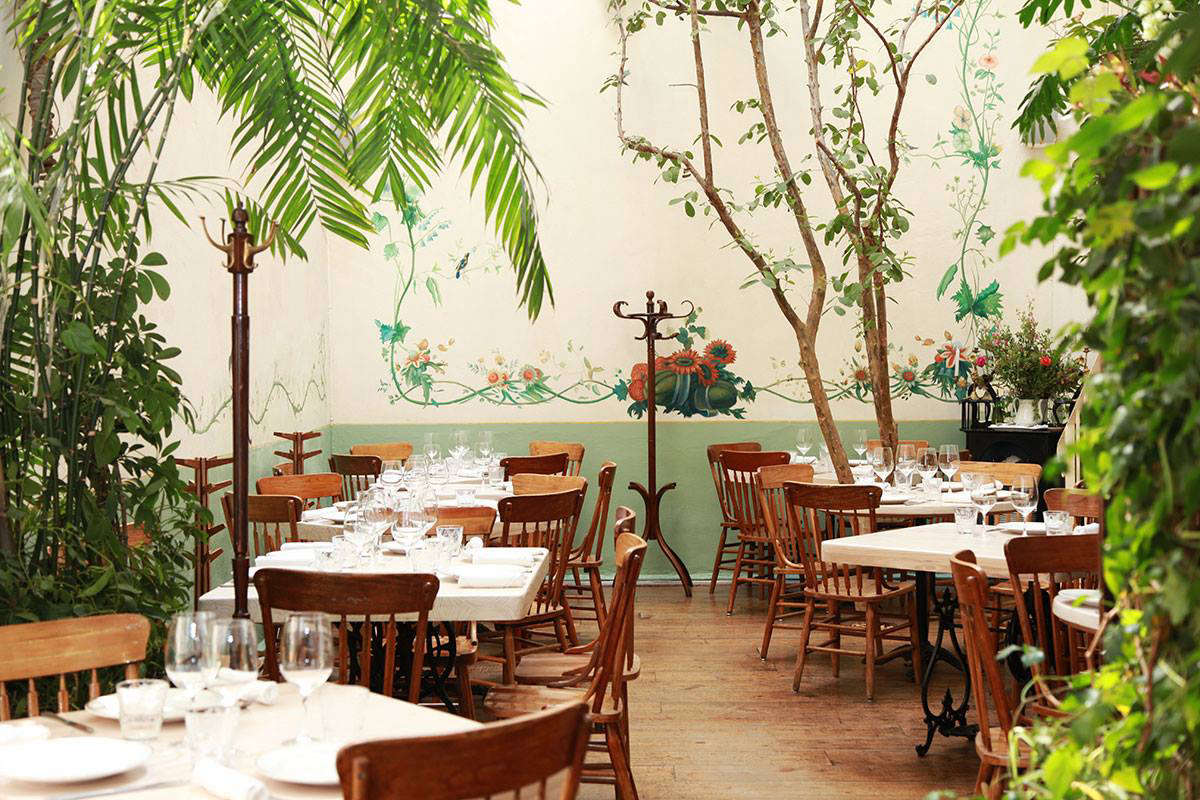 The greenery-filled dining rooms have floral frescos, classic Thonet coat racks, and tables dressed in simple white linens.