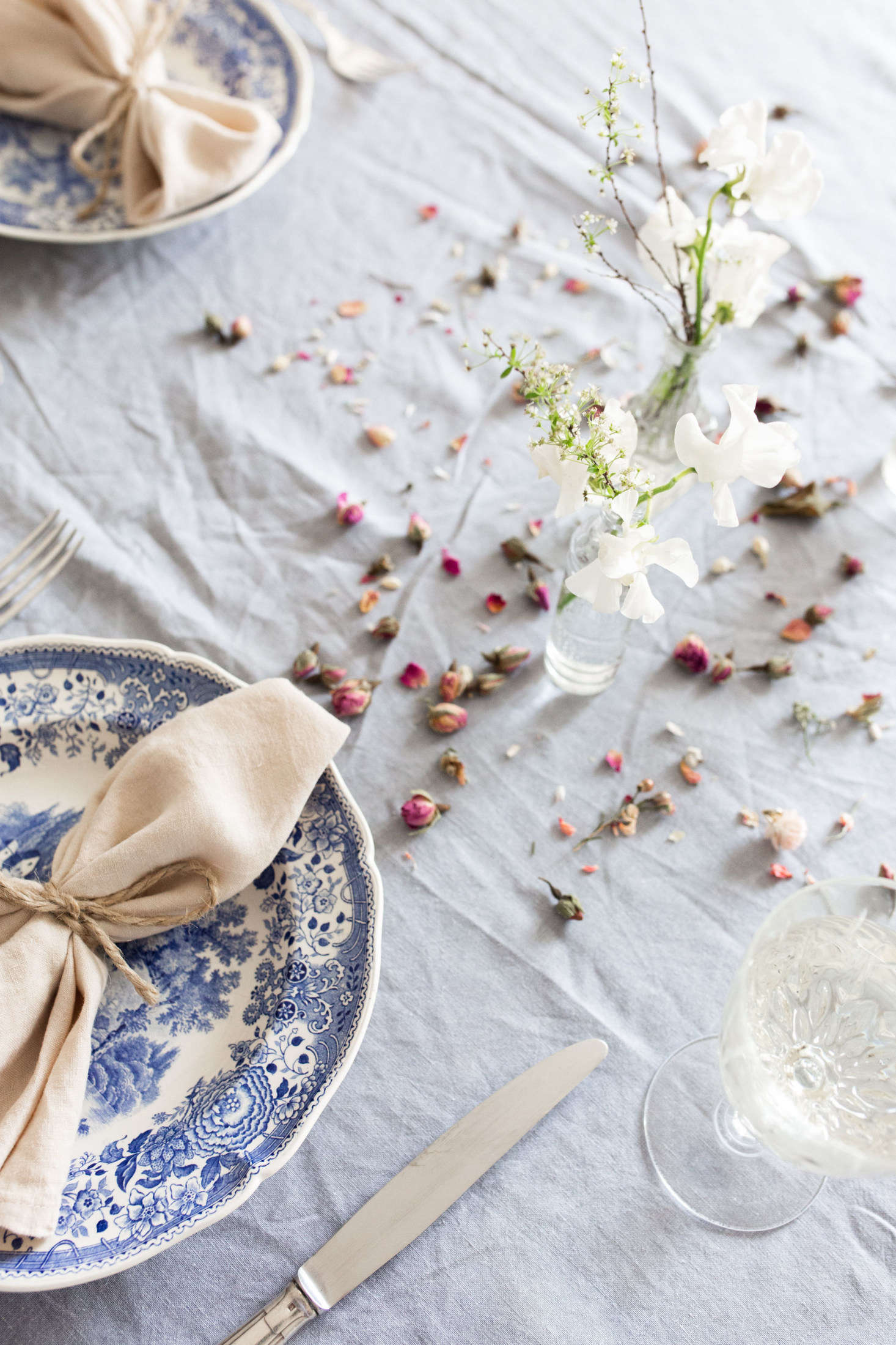 In lieu of a big (quite possibly overpriced) bouquet or centerpiece, tuck just a few small stems into mix-and-match glass jars. This is an intimate dinner at home, remember; the scale should be small. Ajiri used vintage apothecary bottles and vanity jars; simple jam jars work, too.