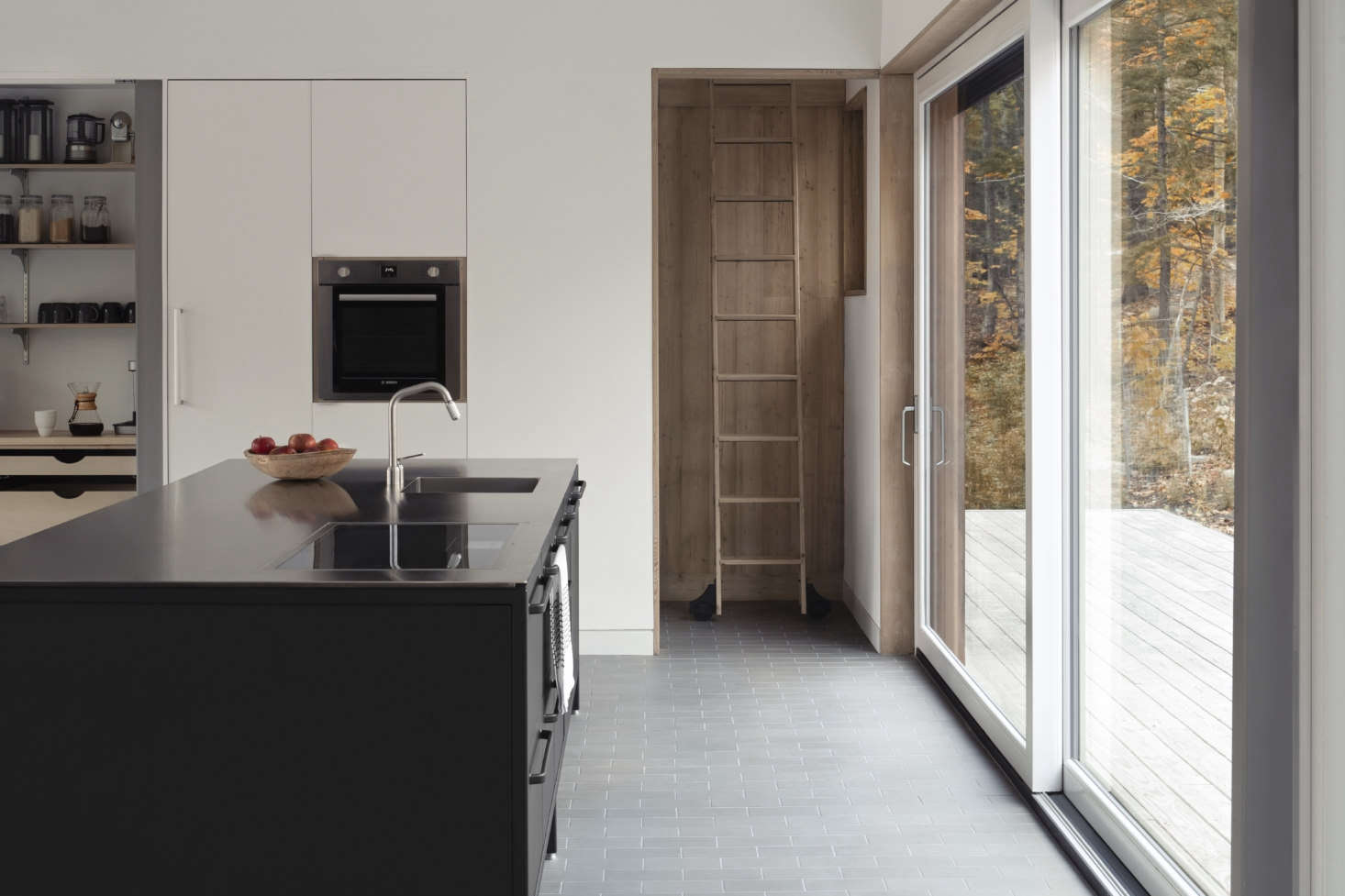 The island is fitted with a sink, dishwasher, and induction cooktop. Additional storage is supplied by a cabinet wall pre-fabricated by Colorado-based CabParts that Marie and Todd painted (Farrow & Ball