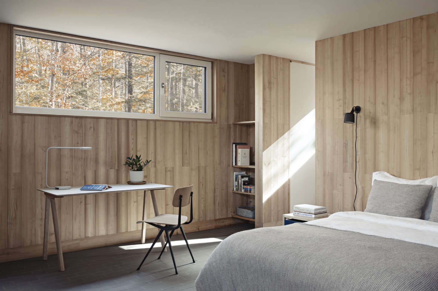 Paneled in larch, the bedrooms have a modernist cabin feel. The desk is the Copenhague 90 by Hay and the bedside sconces are Wall Spots by Vipp.
