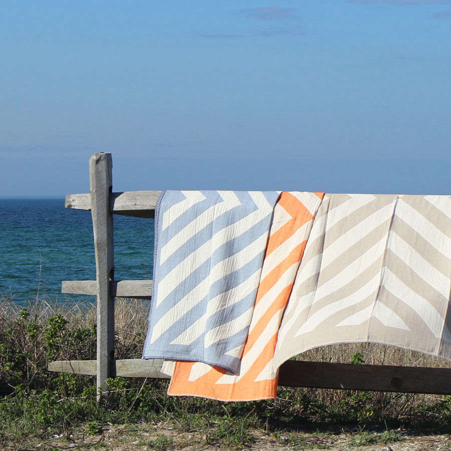 The cotton Lagom Throw ($0, currently on sale for $0), shown here in chambray, tangerine, and taupe. 